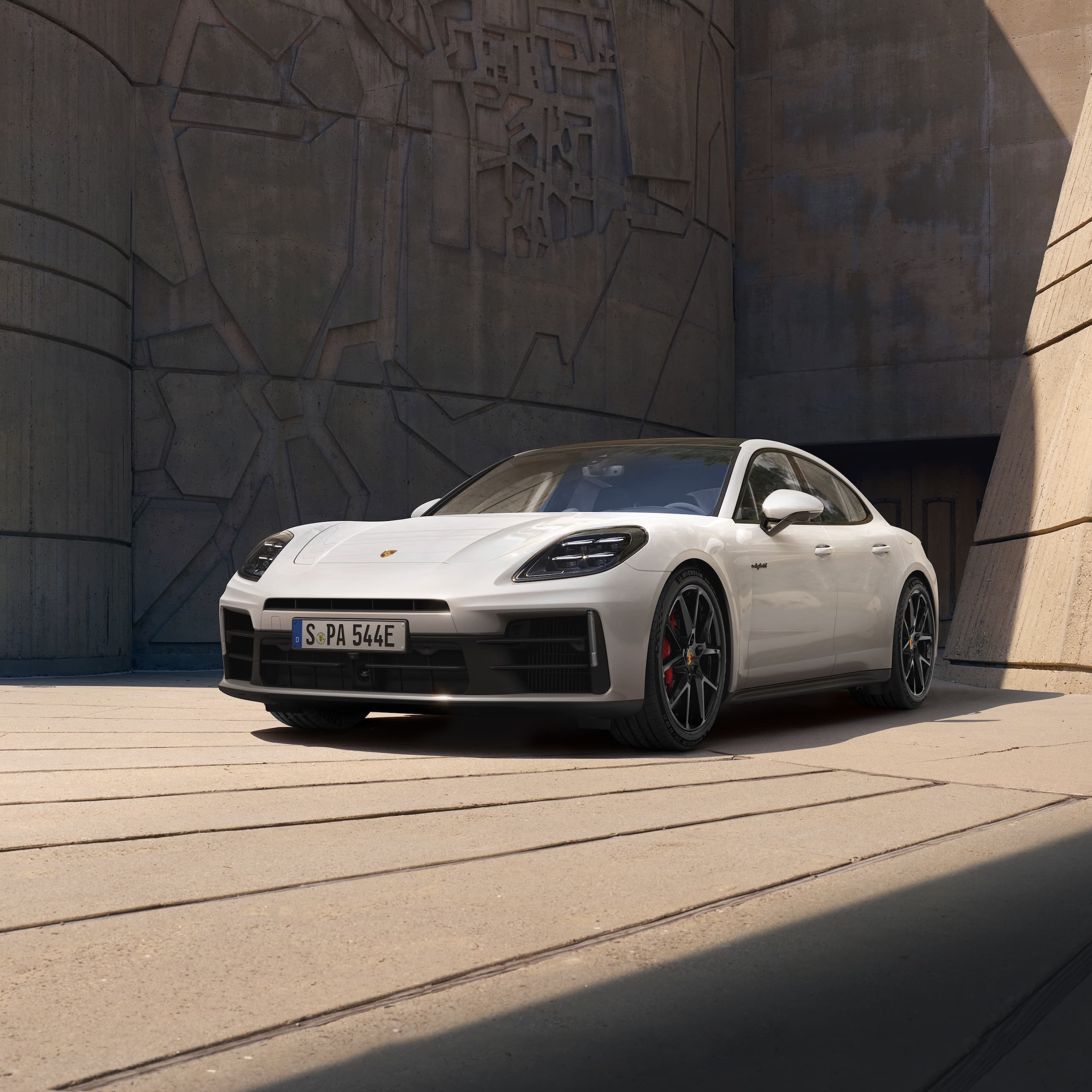 A Porsche Panamera parked in front of a modern building.